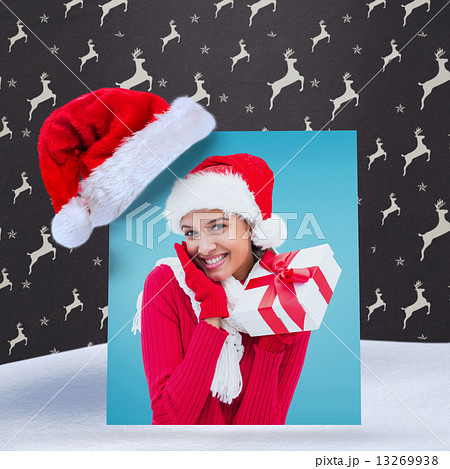 Composite image of festive brunette holding gift Composite image of festive brunette holding gift 13269938