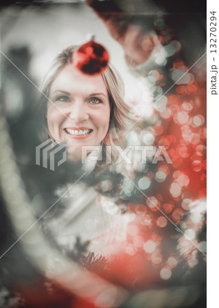 Composite image of festive blonde hanging bauble on christmas tr Composite image of festive blonde hanging bauble on christmas tr 13270294