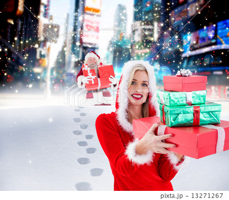 Composite image of festive blonde holding pile of gifts 13271267