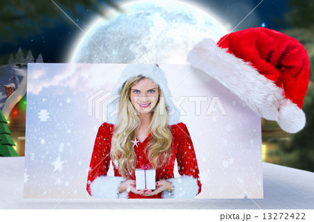 Composite image of pretty girl in santa outfit holding gift Composite image of pretty girl in santa outfit holding gift 13272422