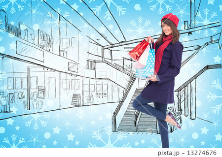 Composite image of happy brunette in winter clothes holding shop 13274676
