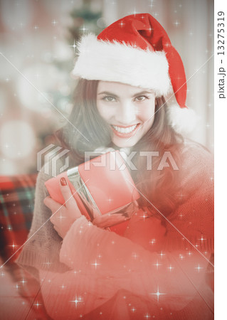 Composite image of festive brunette pressing gift at christmas Composite image of festive brunette pressing gift at christmas 13275319