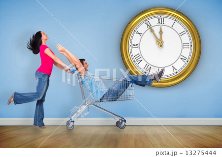 Composite image of young couple having fun with shopping cart 13275444