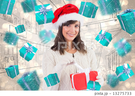 Composite image of smiling young woman in santa hat opening a gi 13275733
