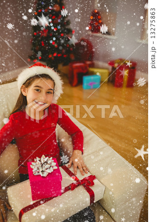 Composite image of festive little girl smiling at camera with gifts 13275863