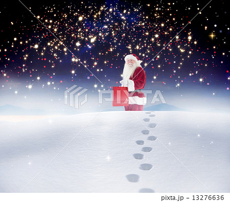 Composite image of santa carrying gifts in the snow 13276636