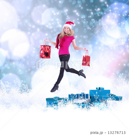 Composite image of festive blonde carrying gift bags 13276713