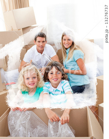 Composite image of smiling family packing boxes Composite image of smiling family packing boxes 13276737