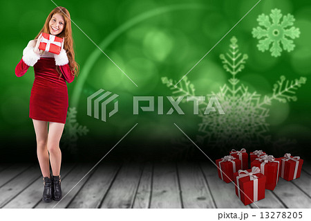 Composite image of festive redhead holding a gift 13278205
