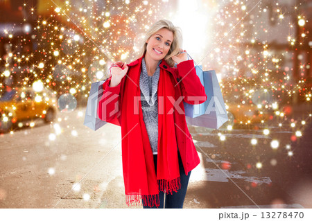 Composite image of blonde in winter clothes holding shopping bag 13278470
