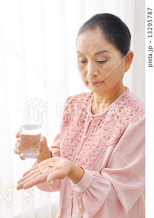 薬を飲む初老の女性 13295787