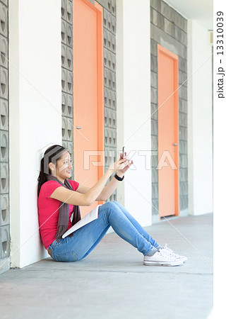 One young pan asian female student taking selfies while studying along campus corridor One young pan asian female student taking selfies while studying along campus corridor 13310039