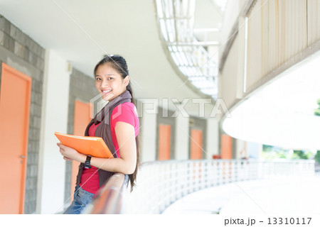 One young pan asian female student standing along campus corridor One young pan asian female student standing along campus corridor 13310117