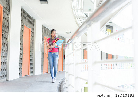 One young pan asian female student going to class along campus corridor 13310193