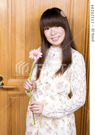 木の壁の前でガーベラの花を持つ女性 13320294