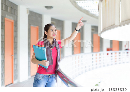 One young pan asian female student pointing a far along campus corridor One young pan asian female student pointing a far along campus corridor 13323339