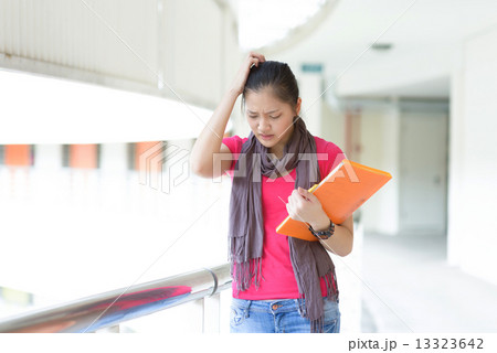 One young pan asian female student stressed over examination along campus corridor One young pan asian female student stressed over examination along campus corridor 13323642