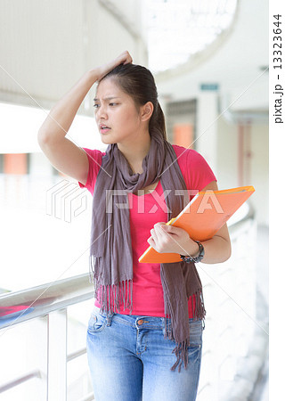 One young pan asian female student stressed over examination along campus corridor 13323644