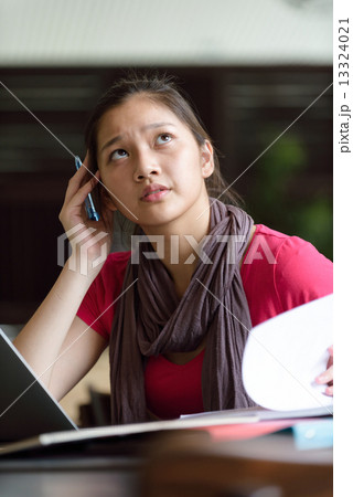 One young pan asian female student stressed over examination in campus cafe 13324021