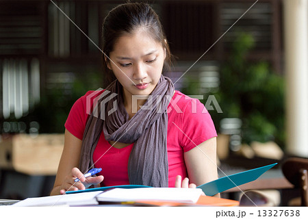 One young pan asian female student studying hard for examination in campus cafe 13327638
