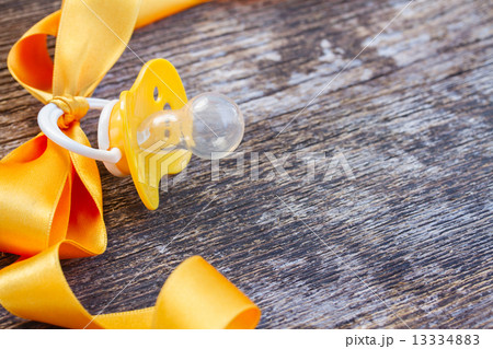 baby pacifier on wooden table 13334883