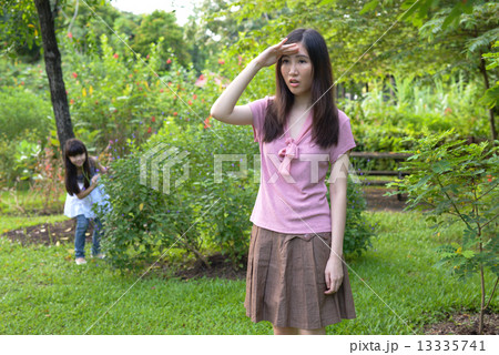 Mother and daughter playing hide and seek in a garden 13335741