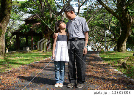 Grandfather and granddaughter strolling in the park 13335808