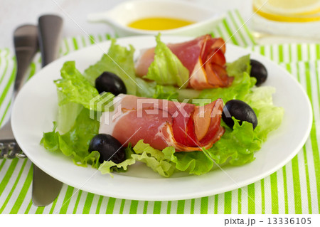 salad with prosciutto and olives on the plate and glass of water salad with prosciutto and olives on the plate and glass of water 13336105