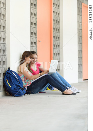 2 young female chinese student using laptop sitting along campus corridor 2 young female chinese student using laptop sitting along campus corridor 13353192