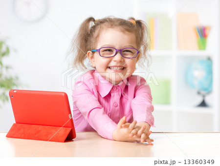 Happy kid with tablet PC in glasses as early education concept Happy kid with tablet PC in glasses as early education concept 13360349