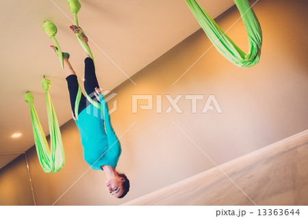 Young woman performing antigravity yoga exercise Young woman performing antigravity yoga exercise 13363644
