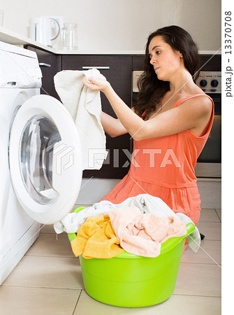 Unhappy girl using washing machine at home Unhappy girl using washing machine at home 13370708