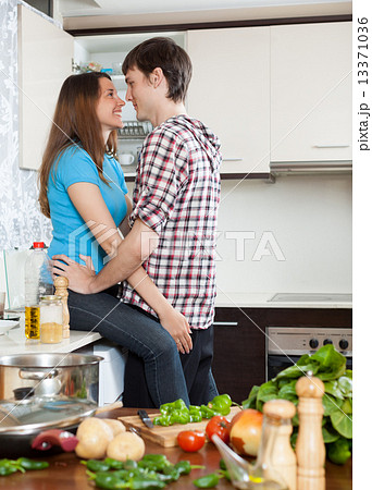 Young loving man and girl having flirt at domestic kitchen Young loving man and girl having flirt at domestic kitchen 13371036