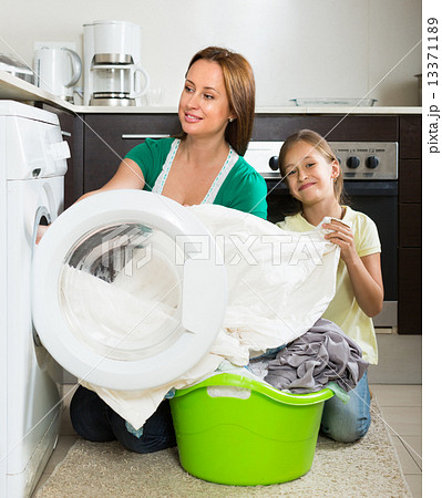 Woman with daughter near washing machine 13371189