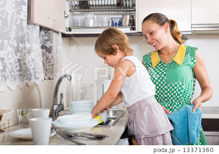 Girl helping mother washing dishes Girl helping mother washing dishes 13371360