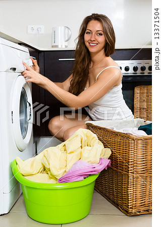 Happy woman washing clothes in washer 13371504