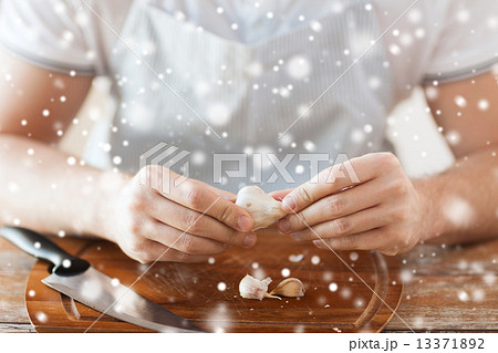 close up of male hands taking off garlic peel 13371892