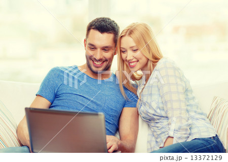 smiling happy couple with laptop at home 13372129