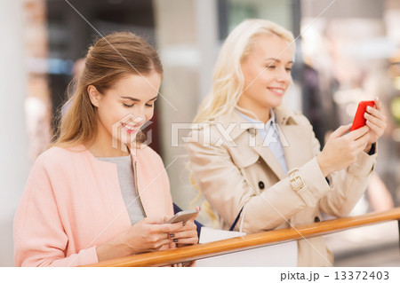 happy women with smartphones and shopping bags 13372403