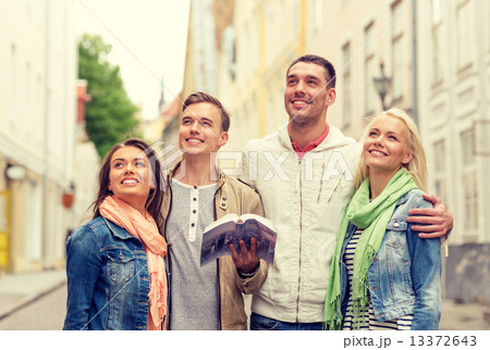group of friends with city guide exploring town 13372643