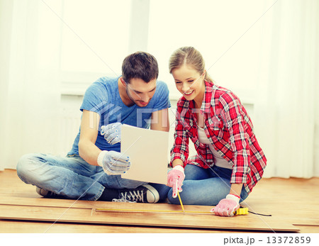 smiling couple measuring wood flooring 13372859