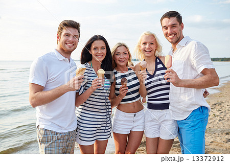 smiling friends eating ice cream on beach 13372912