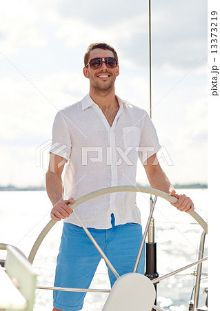 young man in sunglasses steering wheel on yacht 13373219