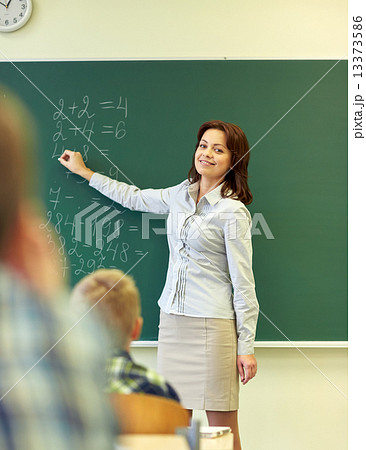 school kids and teacher writing on chalkboard 13373586