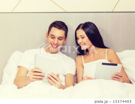 smiling couple in bed with tablet pc computers 13374403