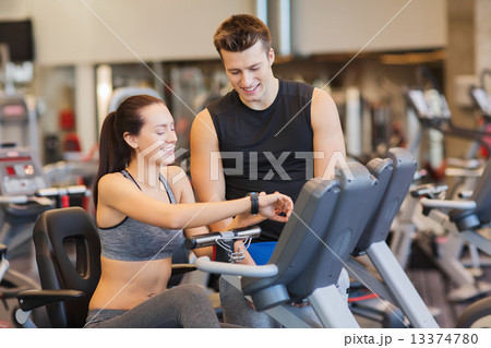 happy woman with trainer on exercise bike in gym 13374780
