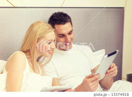 smiling couple in bed with tablet pc computers smiling couple in bed with tablet pc computers 13374918