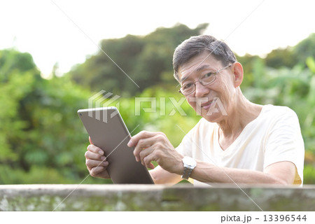 One male chinese elderly using iPad in the park 13396544