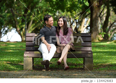 1 chinese couple sitting on wooden bench in a park 13442683