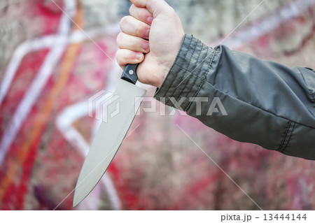Hand with knife near old wall  13444144